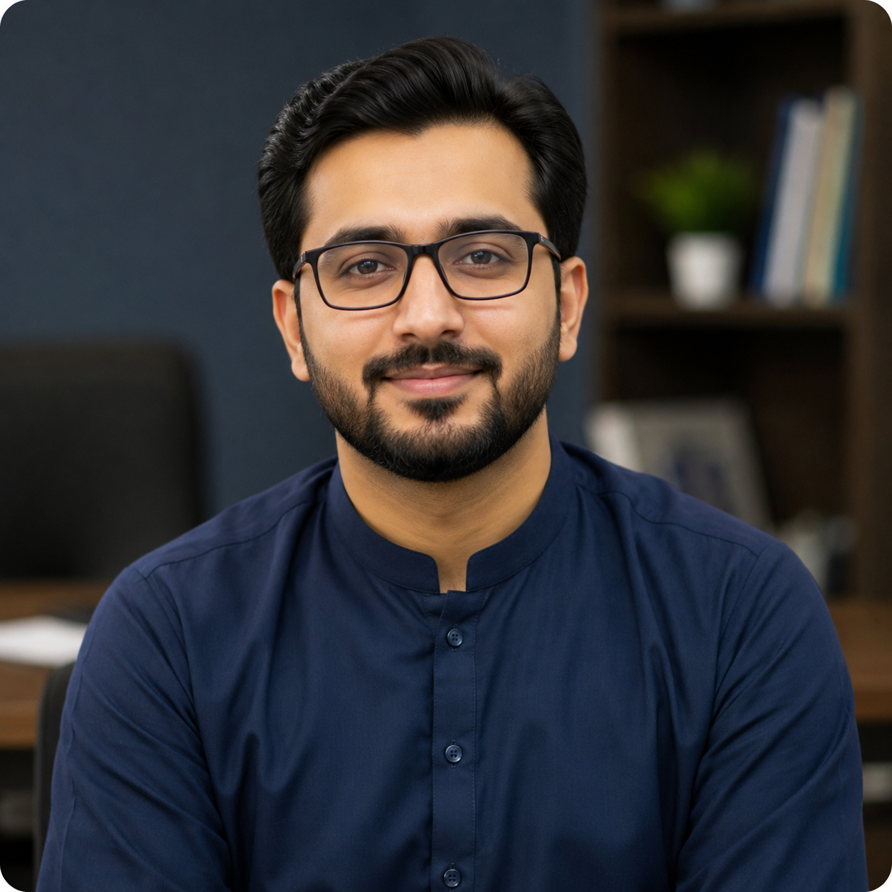 Portrait of a smiling man with dark hair, glasses, and a beard