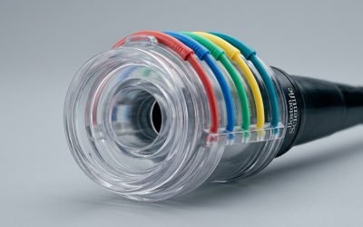 A close-up of a multi-band ligator device loaded with small black elastic bands on its transparent barrel, the instrument used to place bands on esophageal varices during EVBL.