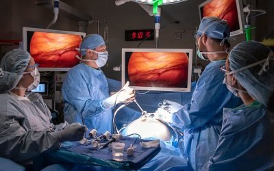 Surgical team in an operating room performing a procedure with monitors showing internal views