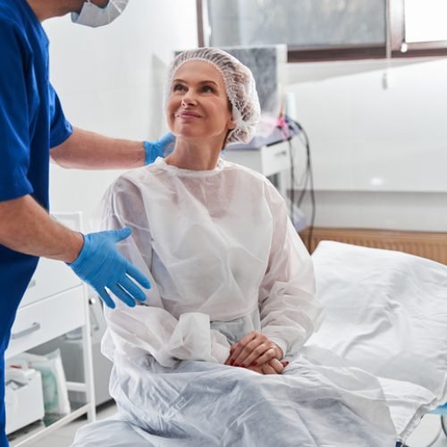 Clinician calming a smiling patient sitting on a procedure bed before gastroscopy